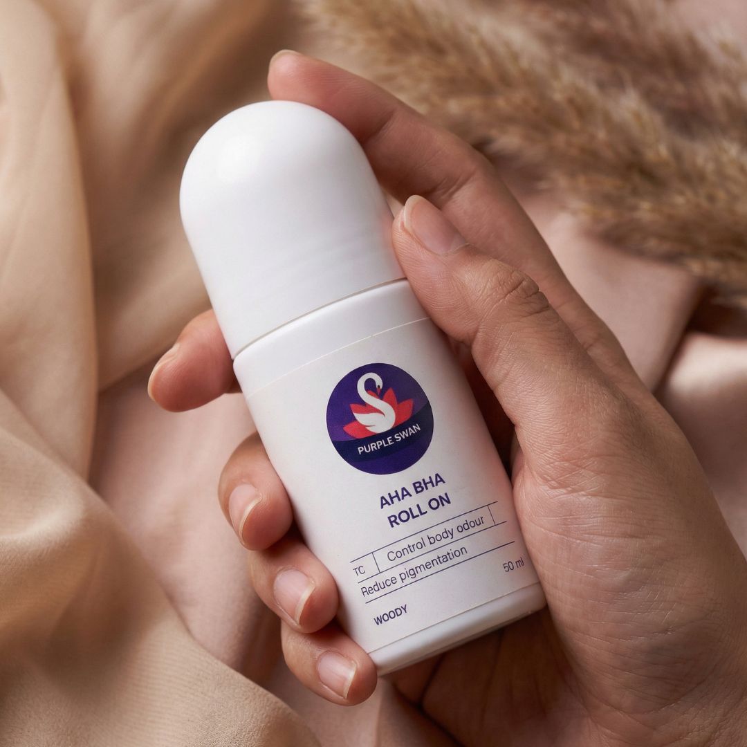 Hand holding Purple Swan AHA BHA roll on deodorant