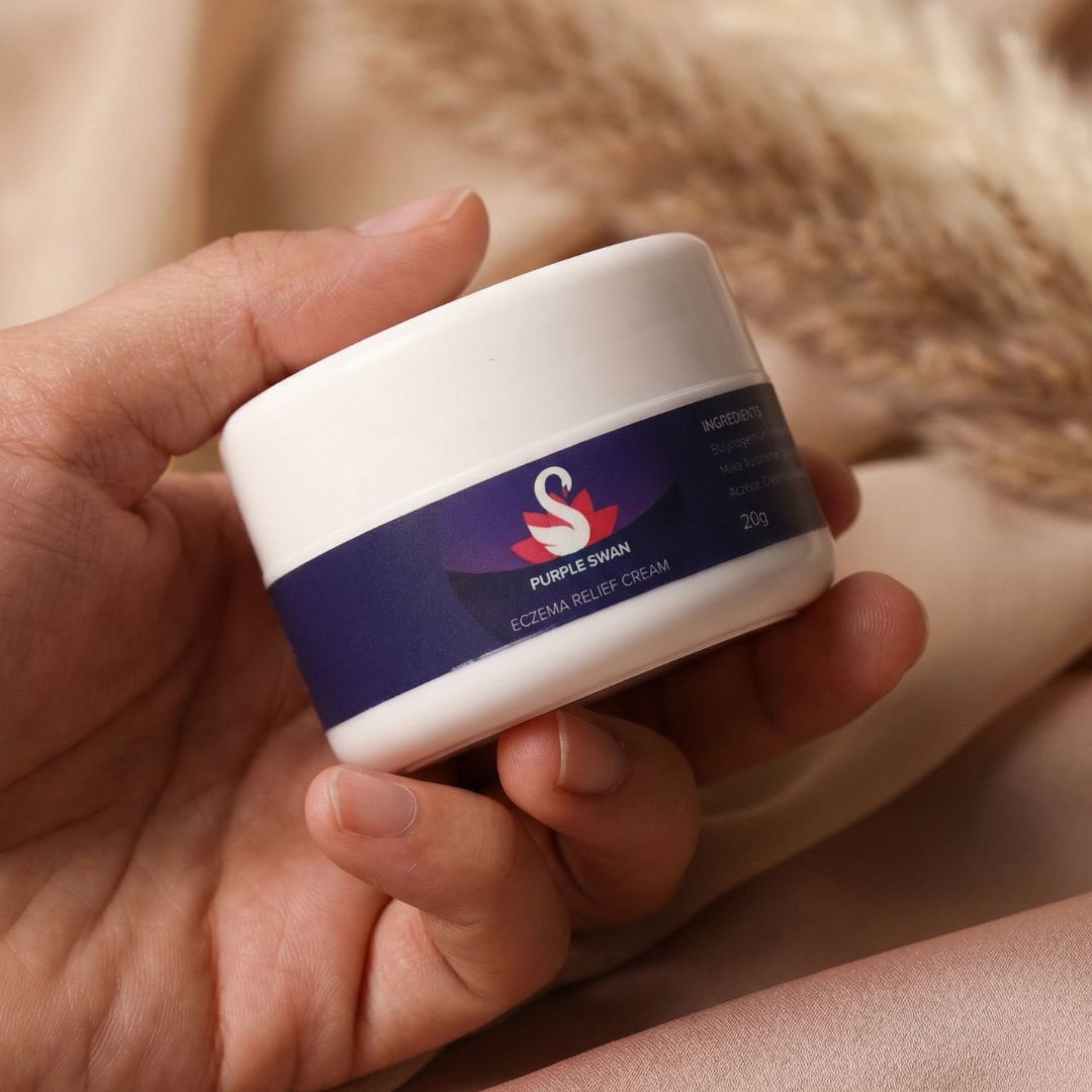 Hand holding Purple Swan eczema relief cream skincare container