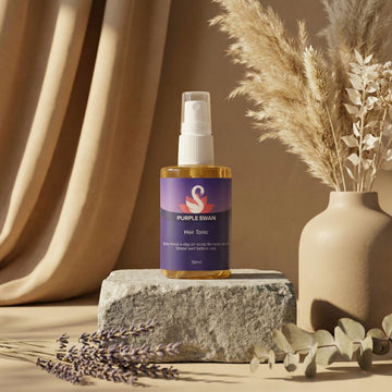 Hair tonic bottle labeled 'Purple Swan' on a stone surface with decorative elements.