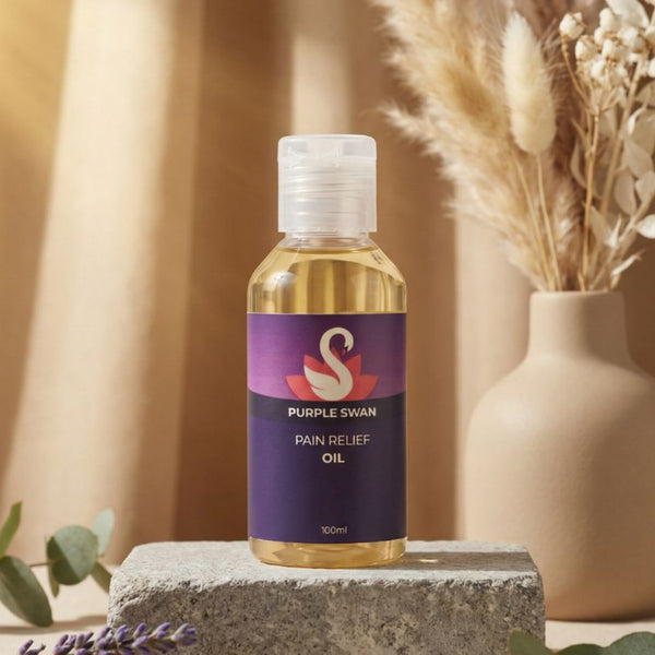 Bottle of Purple Swan Pain Relief Oil on a stone block with decorative elements in the background