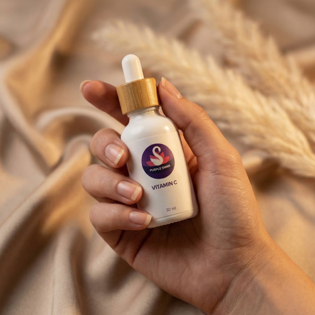 Hand holding Purple Swan vitamin C serum skincare bottle